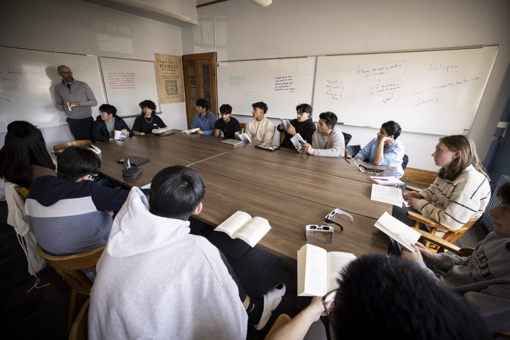 Matt Roach teaching his English class with students sitting around a big table