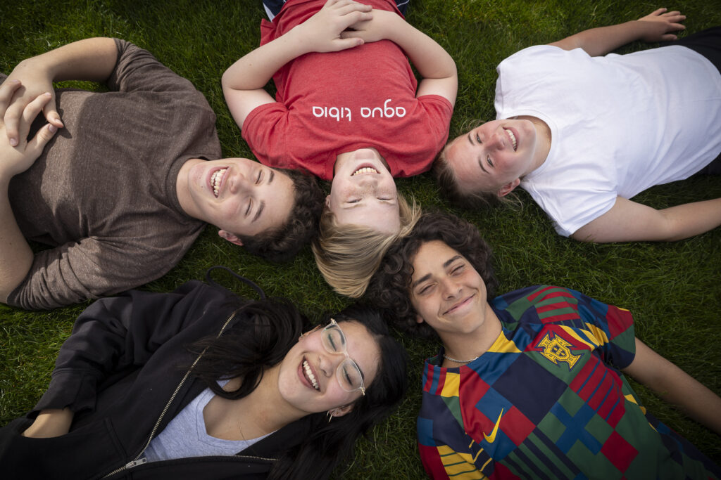 students laying on their backs on the ground outside with their heads in a circle