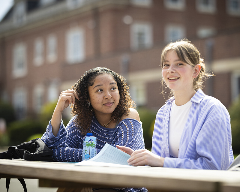 Two girls studying outside at a picnic table